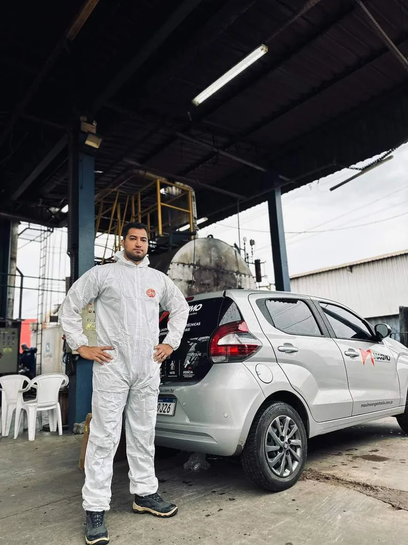 Profissional da Máximo Engenharia uniformizado, ao lado do veículo da empresa, em atendimento numa área industrial.